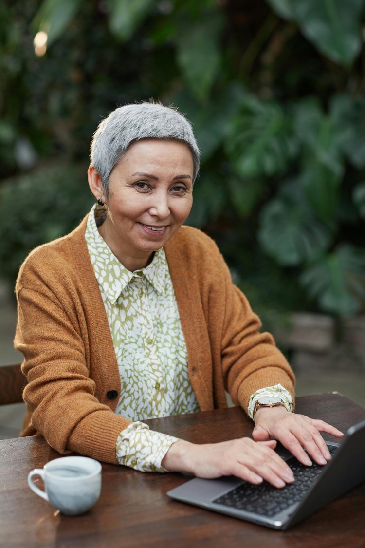 An older woman enjoying time outdoors with her laptop